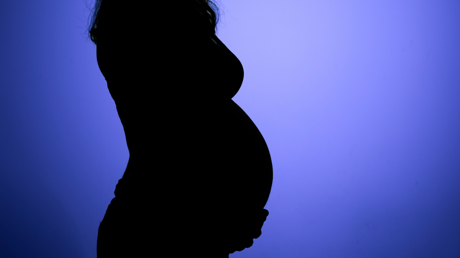 Silhouette d'une femme enceinte de profil, tenant son ventre, sur un fond violet éclatant.